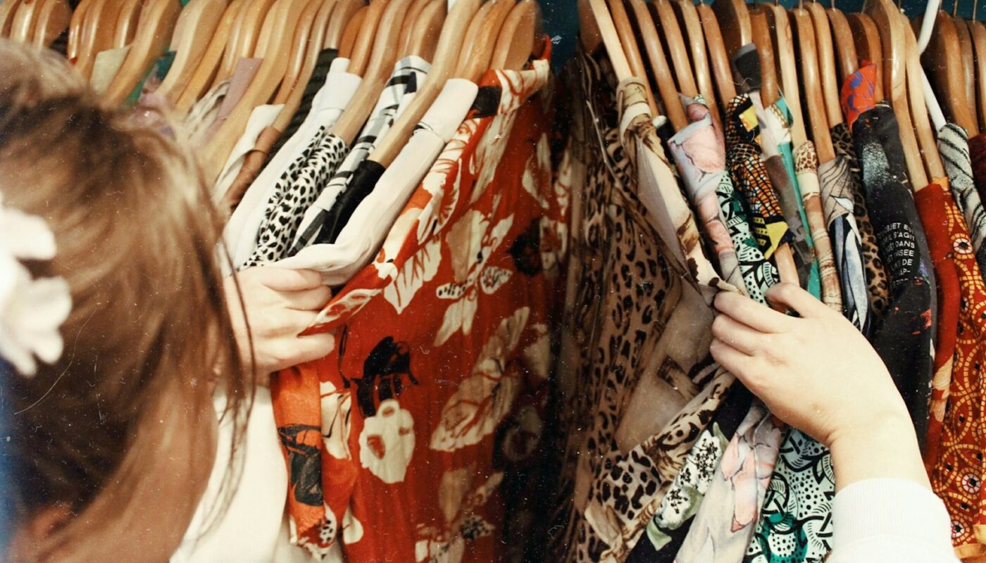 person holding assorted clothes in wooden hanger