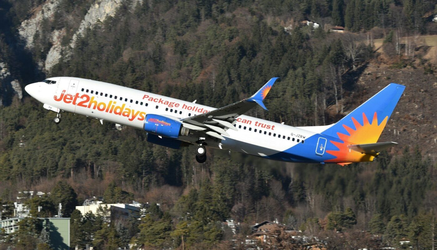 A jet2holidays airplane takes off near mountains.