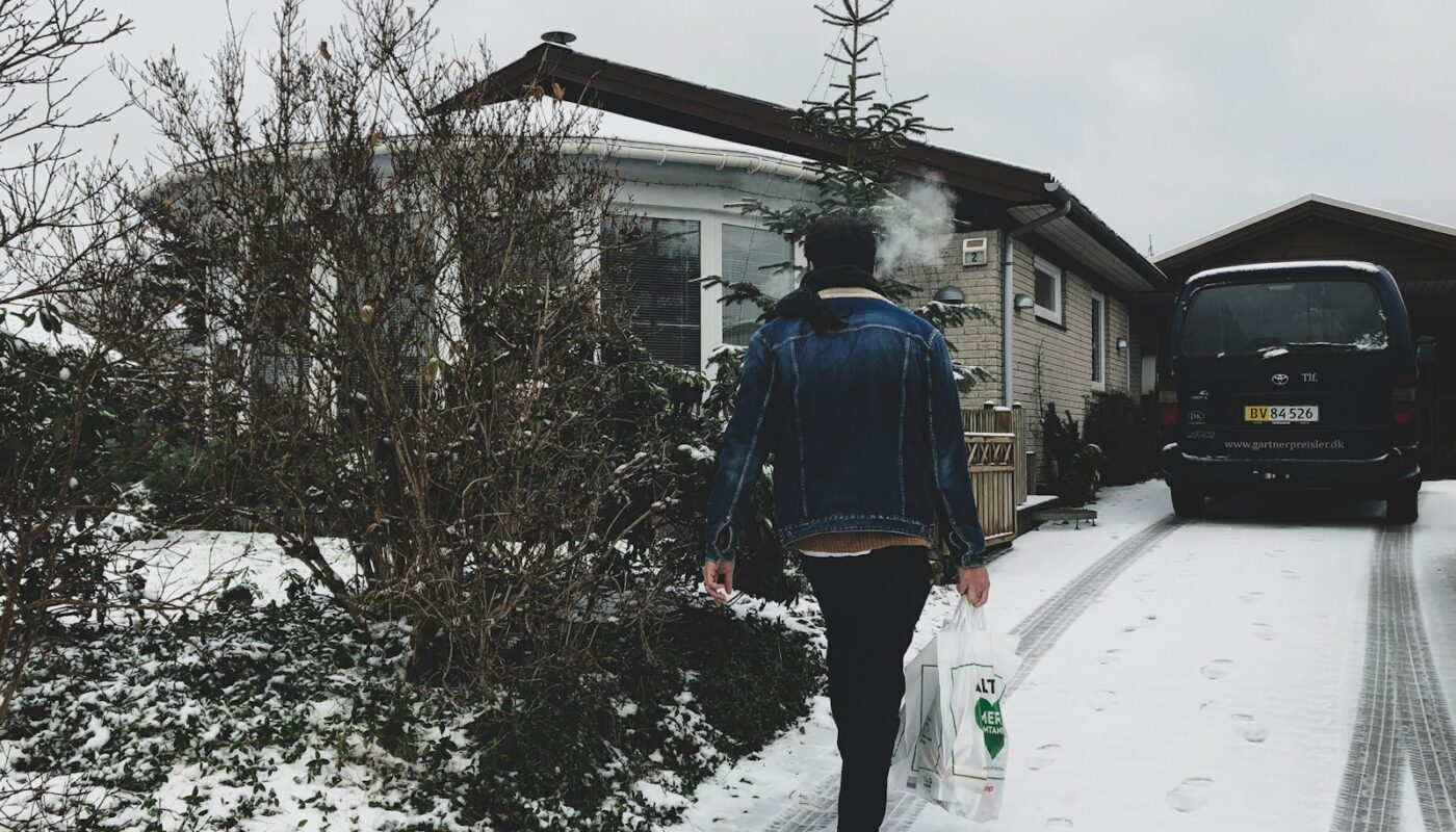 woman carrying plastic bag walking near house during winter